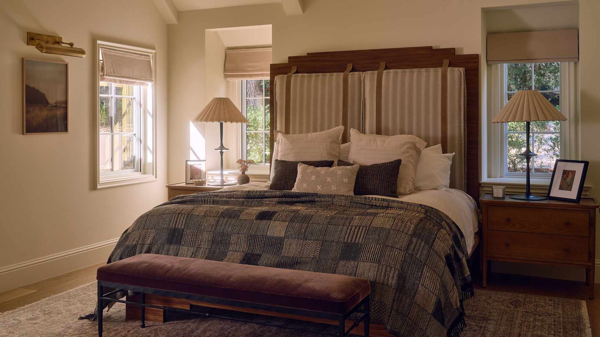 a large primary bedroom suite with a tall wooden and upholstered bed with patchwork quilt