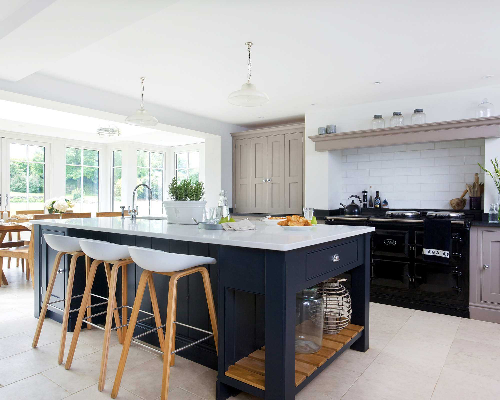 A large white open plan kitchen idea with breakfast bar and midnight blue cabinetry.