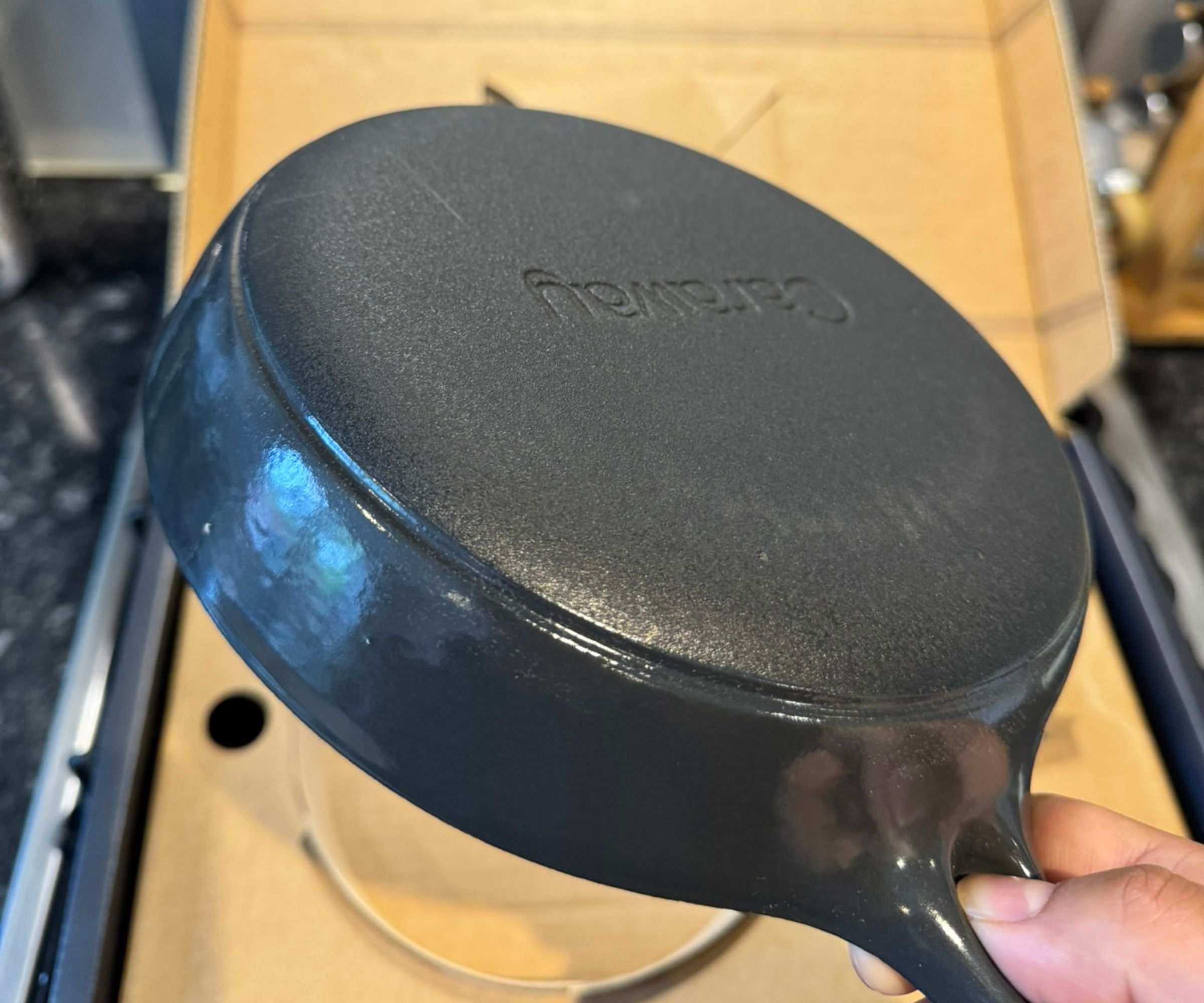 The rough base of the black cast iron mini skillet, being held over the box.