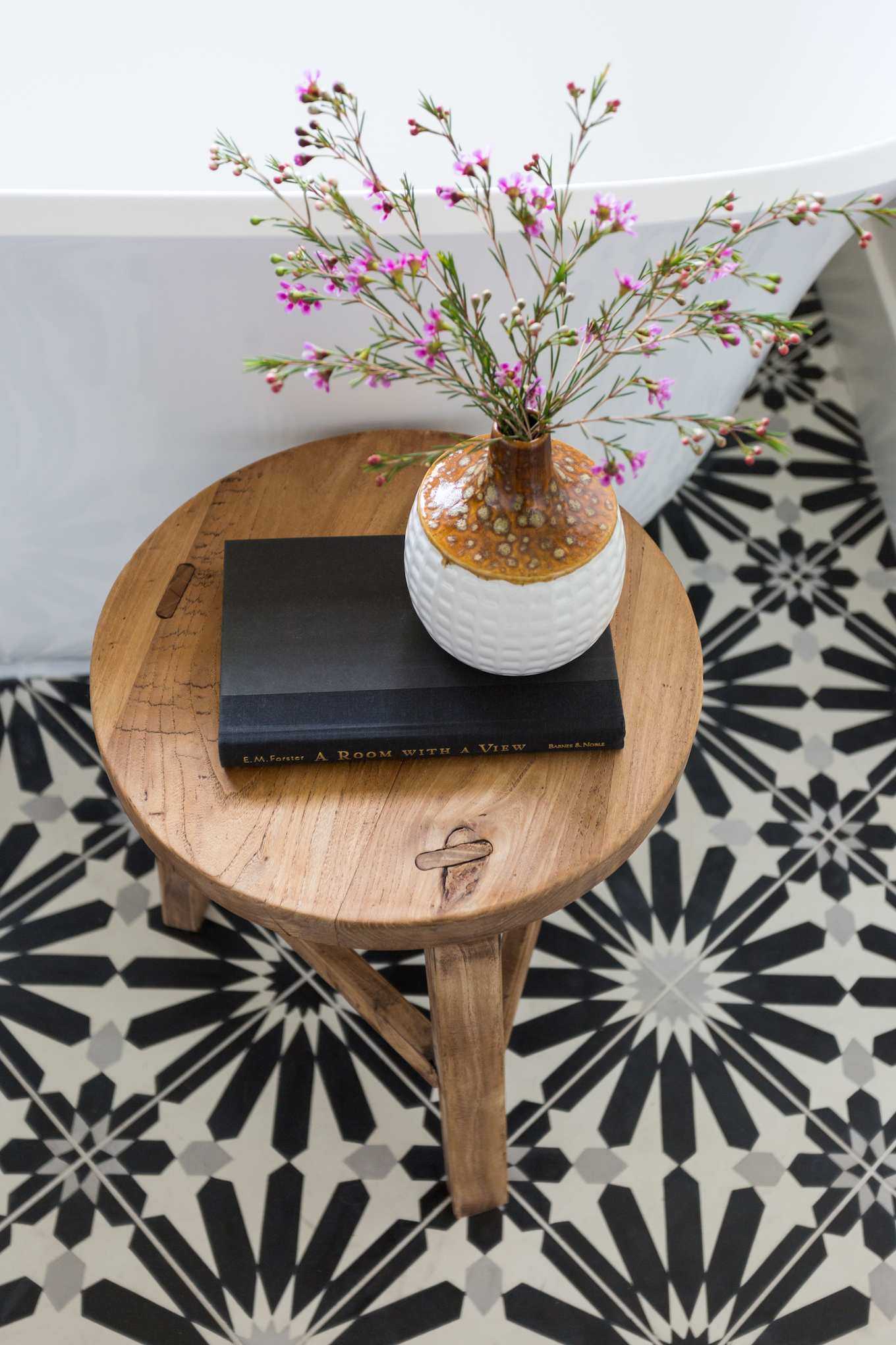 farmhouse bathroom with monochrome pattern tile, round wooden stool with flowers