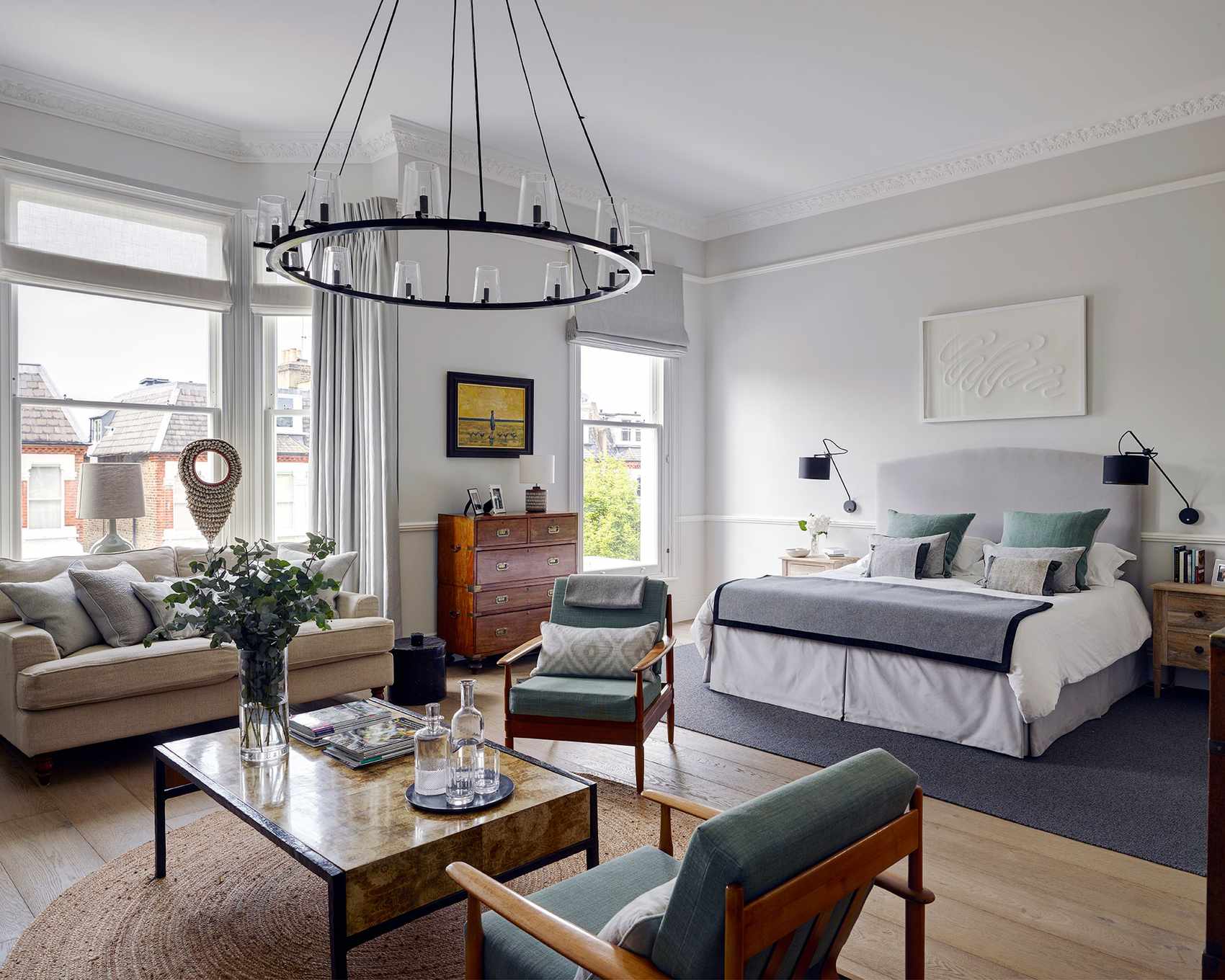 A large bedroom with grand ceiling lighting above a lounge area and white walls