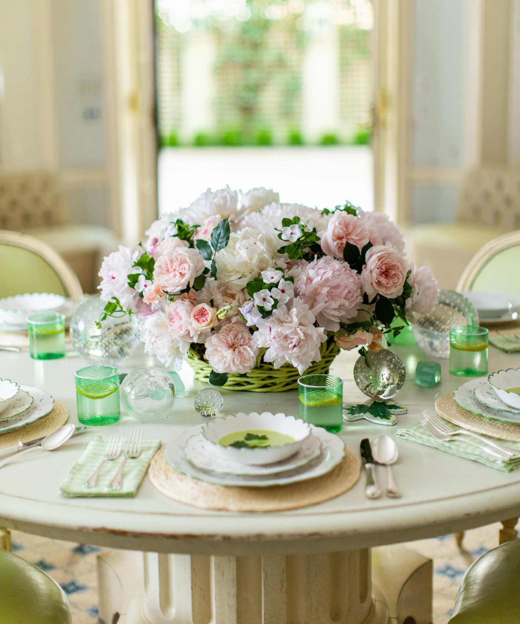 Spring table with peonies bouquet and green glasses and china plates