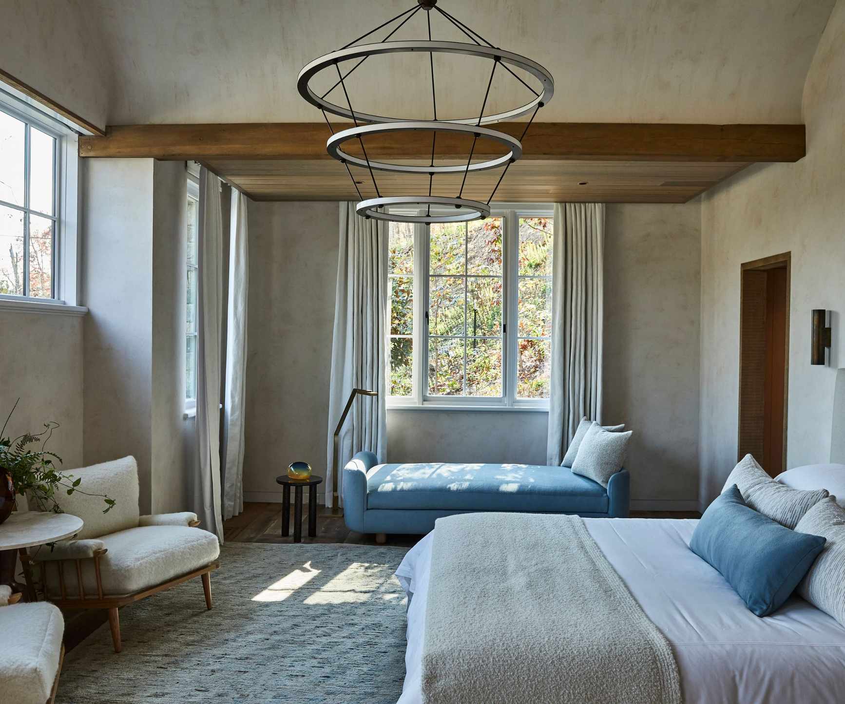 Neutral bedroom with wood beams, statement pendant light and double bed and day bed