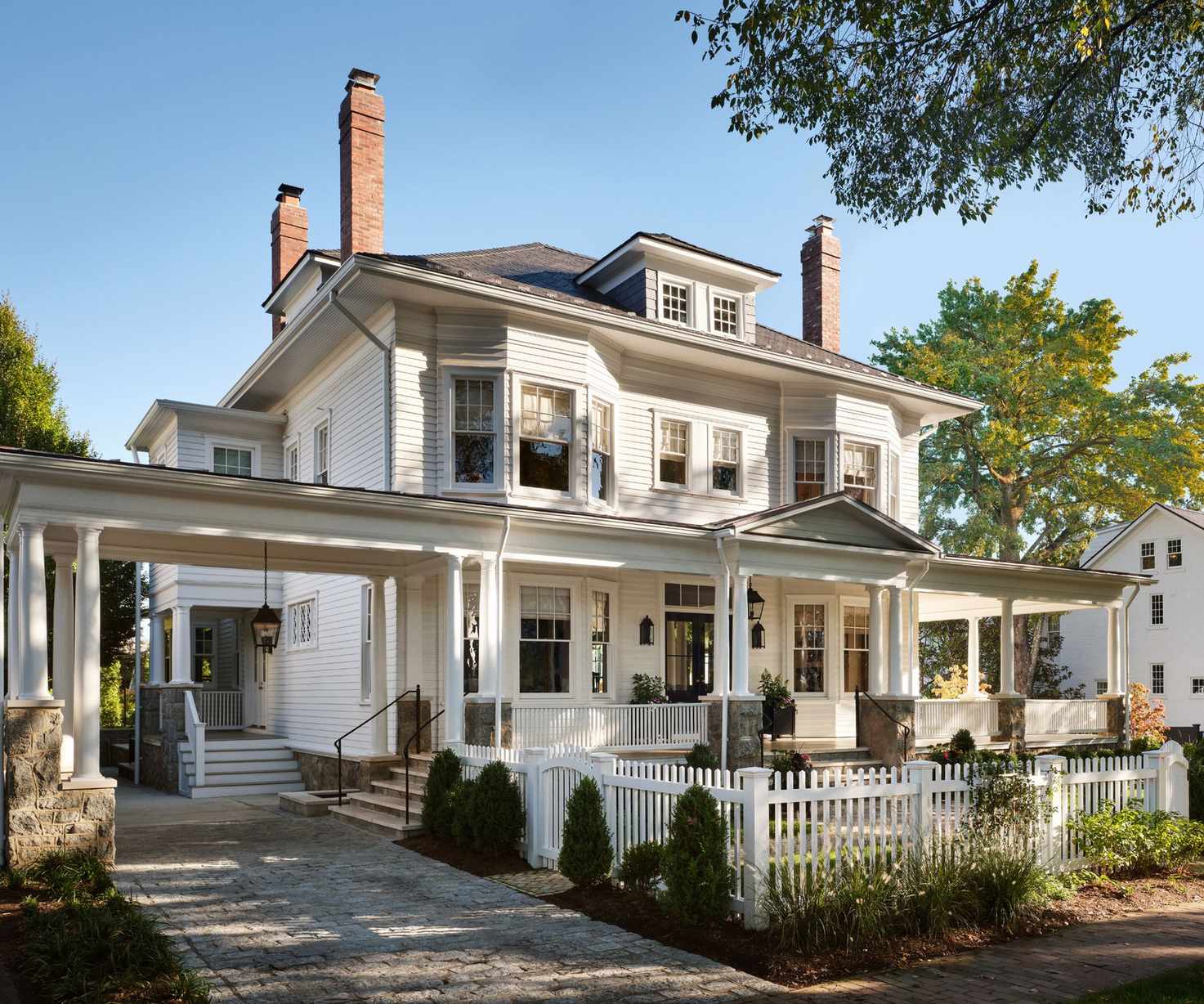 Exterior of a queen anne style home with white panelling and white picket fence