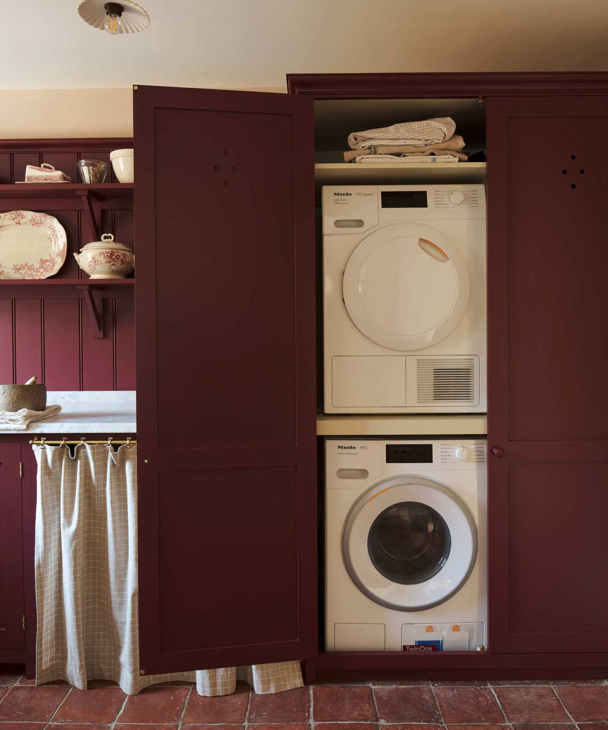 A burgundy laundry room with stacked appliances