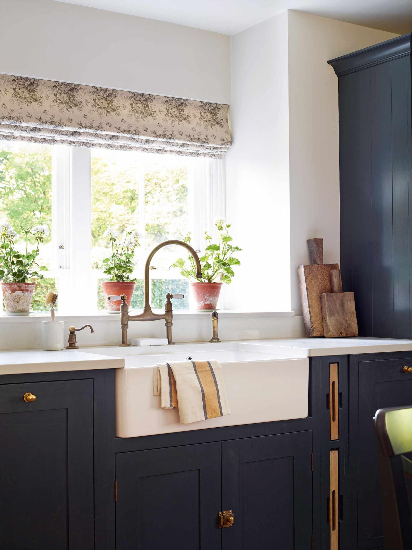 butler's sink by window with floral blind and blue kitchen cabinets