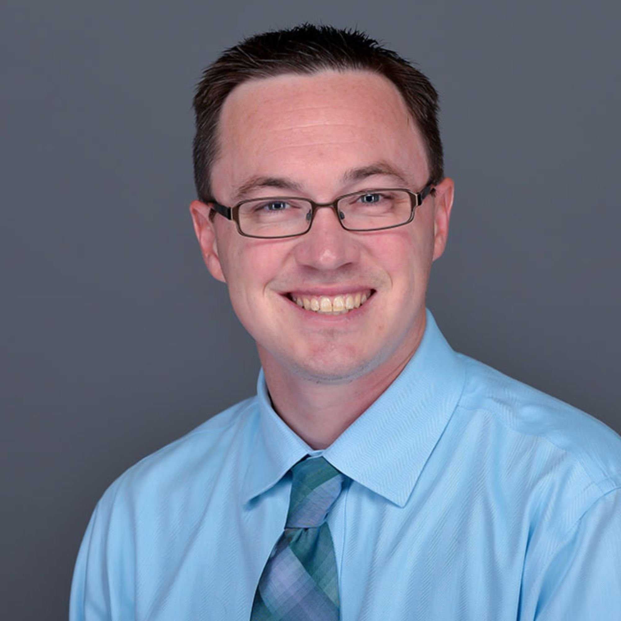 A headshot of Dr. Andrew Gall wearing a blue shirt