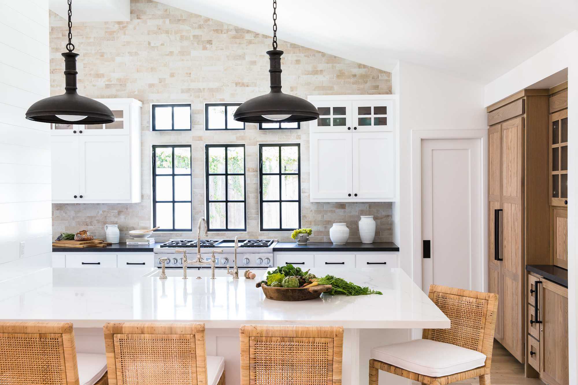 modern farmhouse dining room with woven back leather chairs white walls and black wall lights
