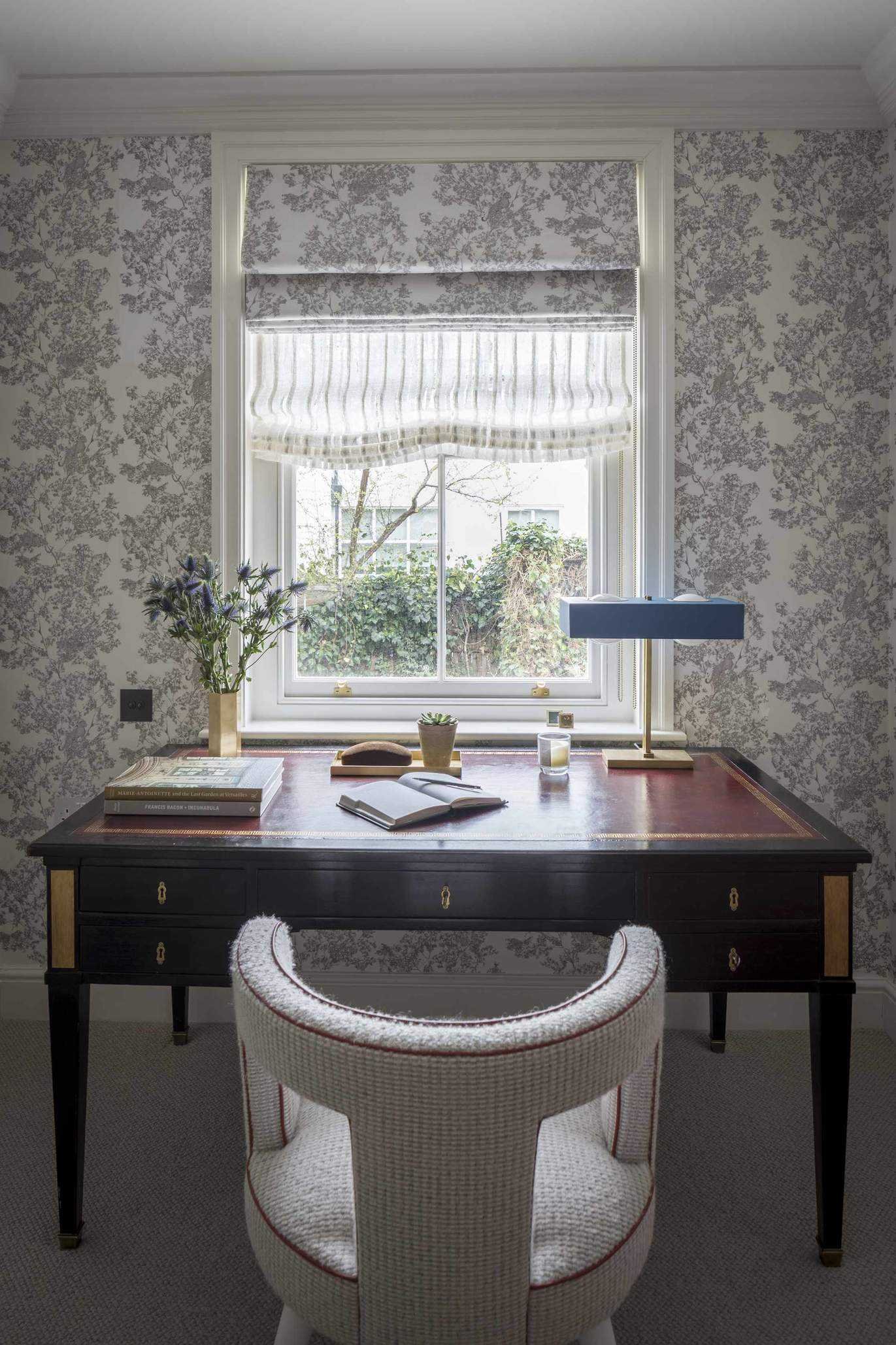 desk in front of a window with roman blinds, lamp and stationery