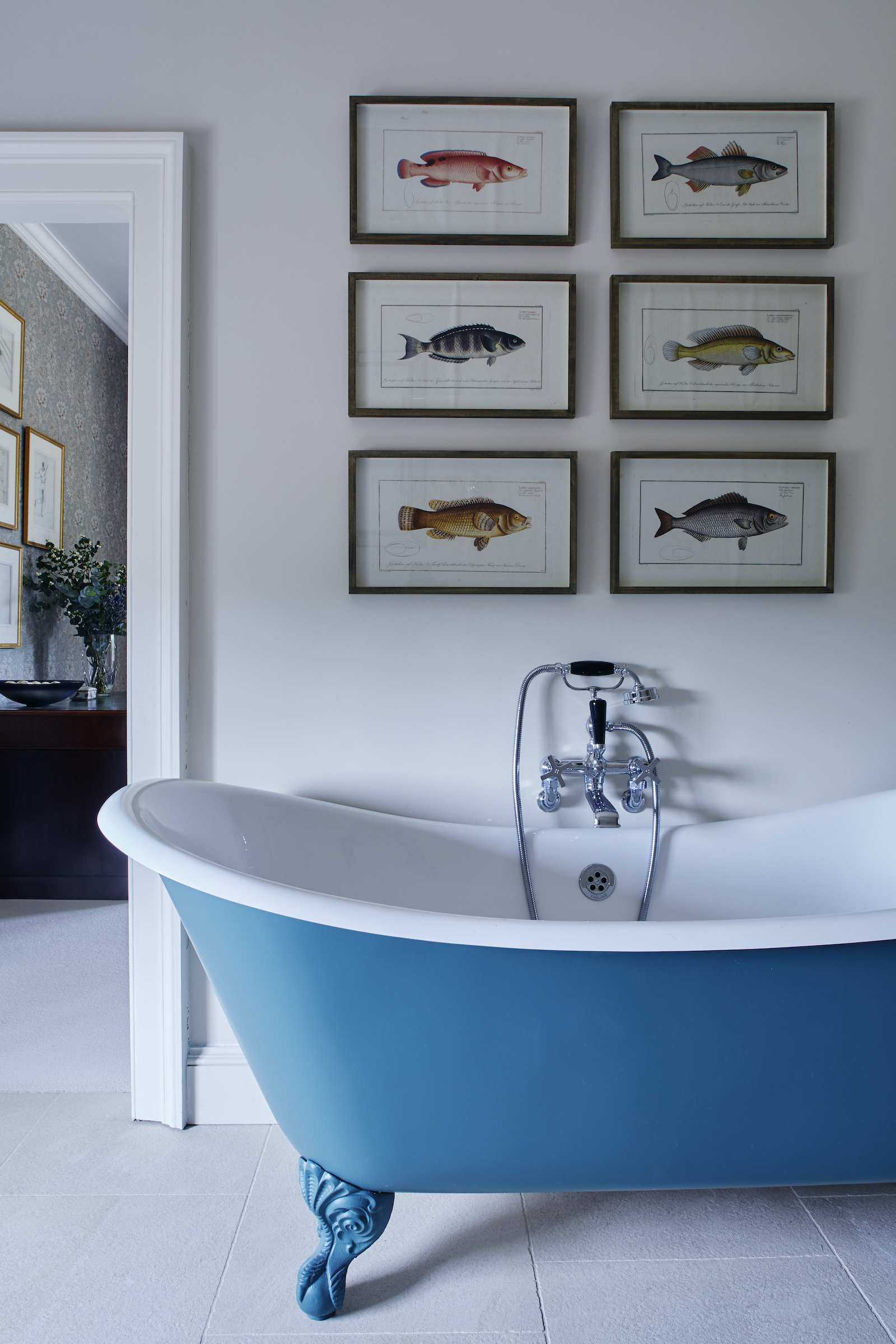 bathroom with blue painted bath and fish artworks on wall