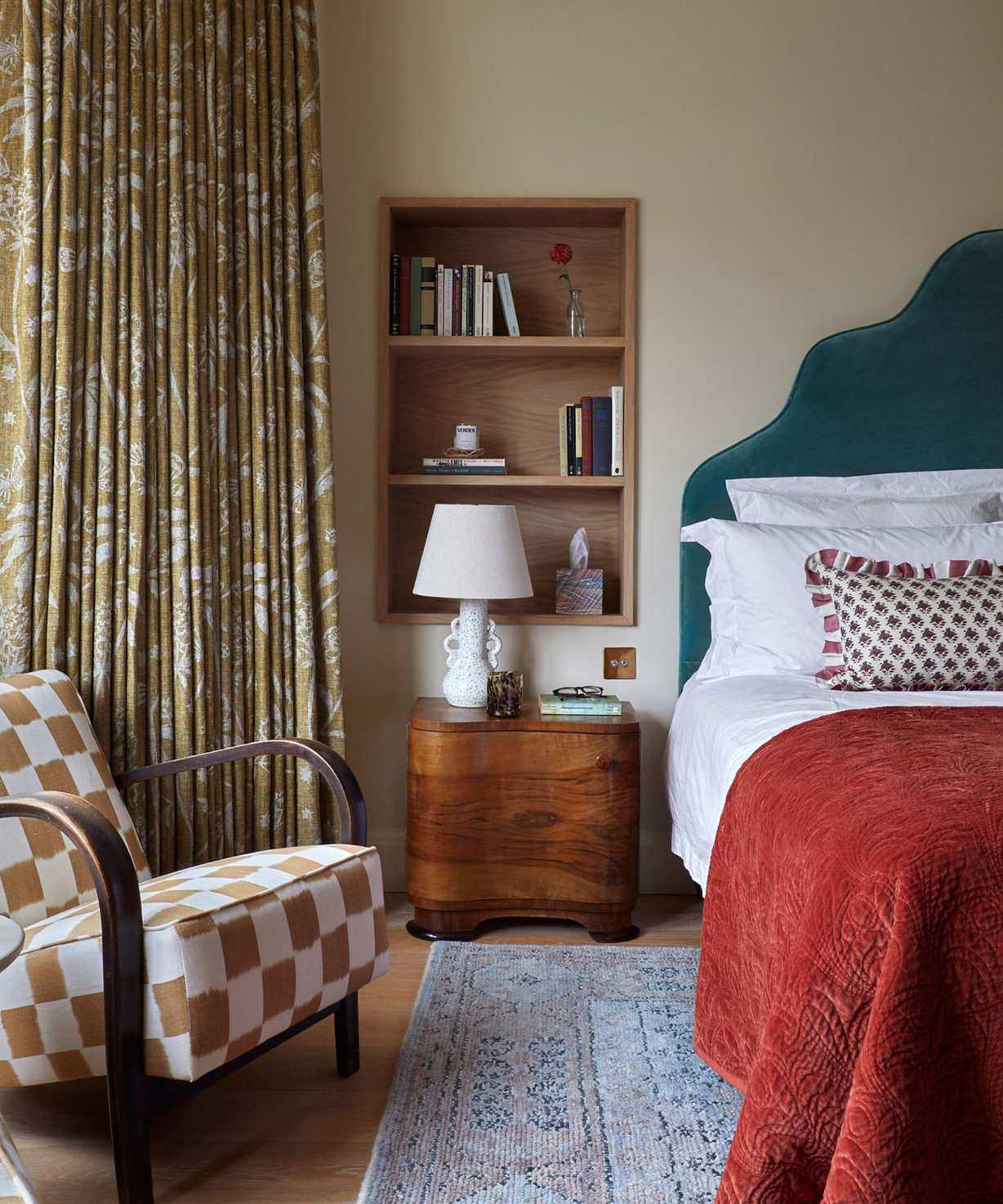 neutral bedroom with green headboard, red throw blanket and a built-in shelf niche