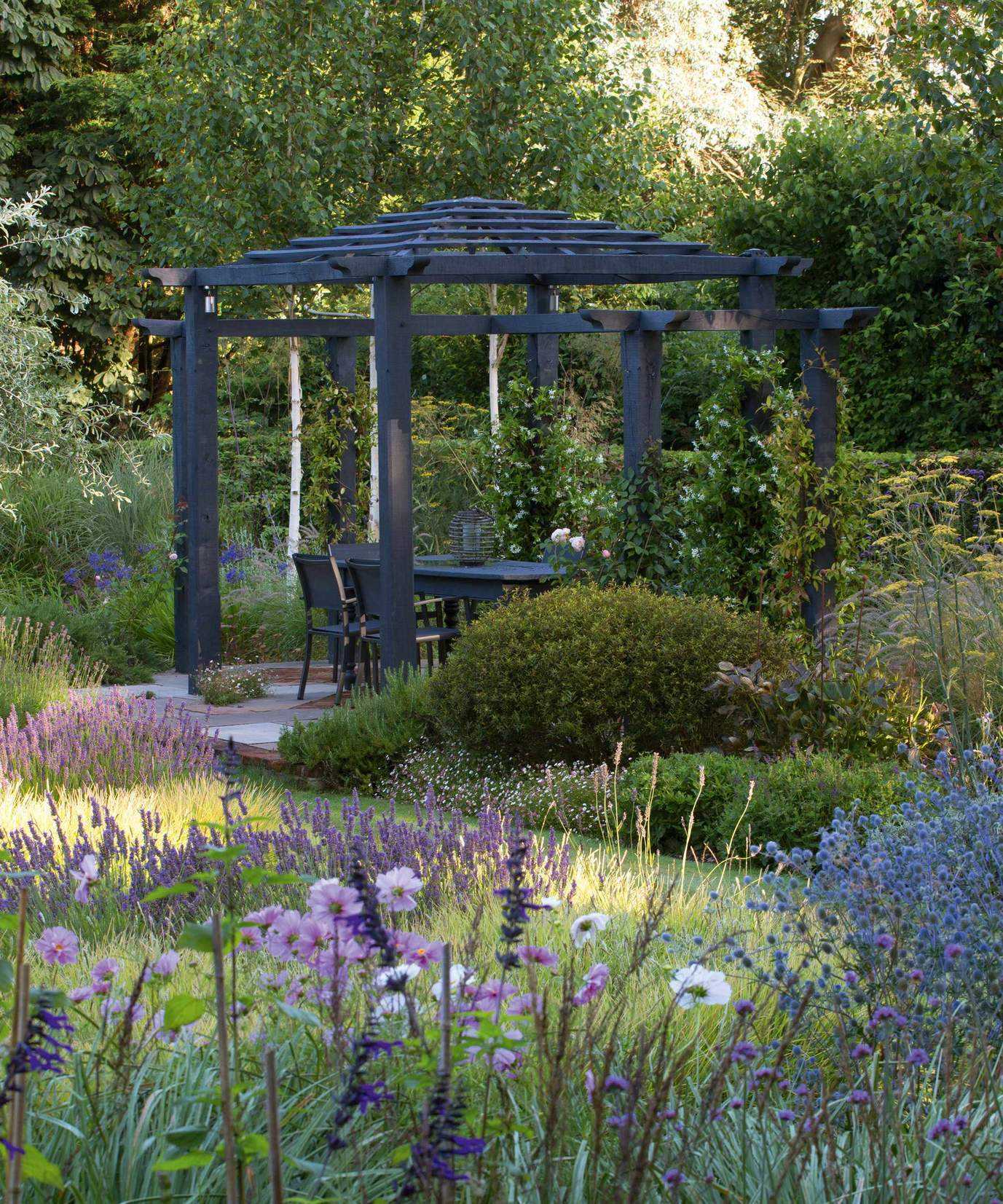 pergola used for dining area among the flowers in a summer garden