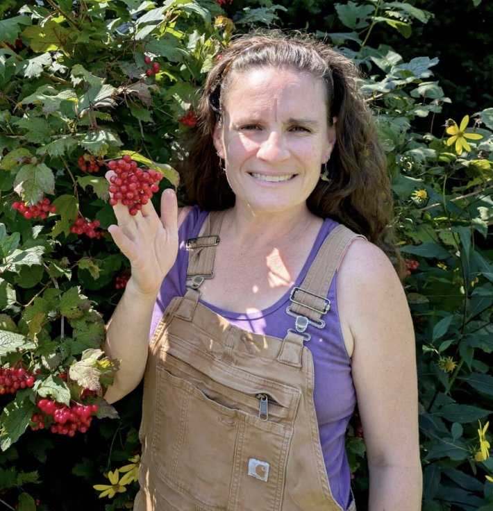 Woman in dungarees smiling and holding flower