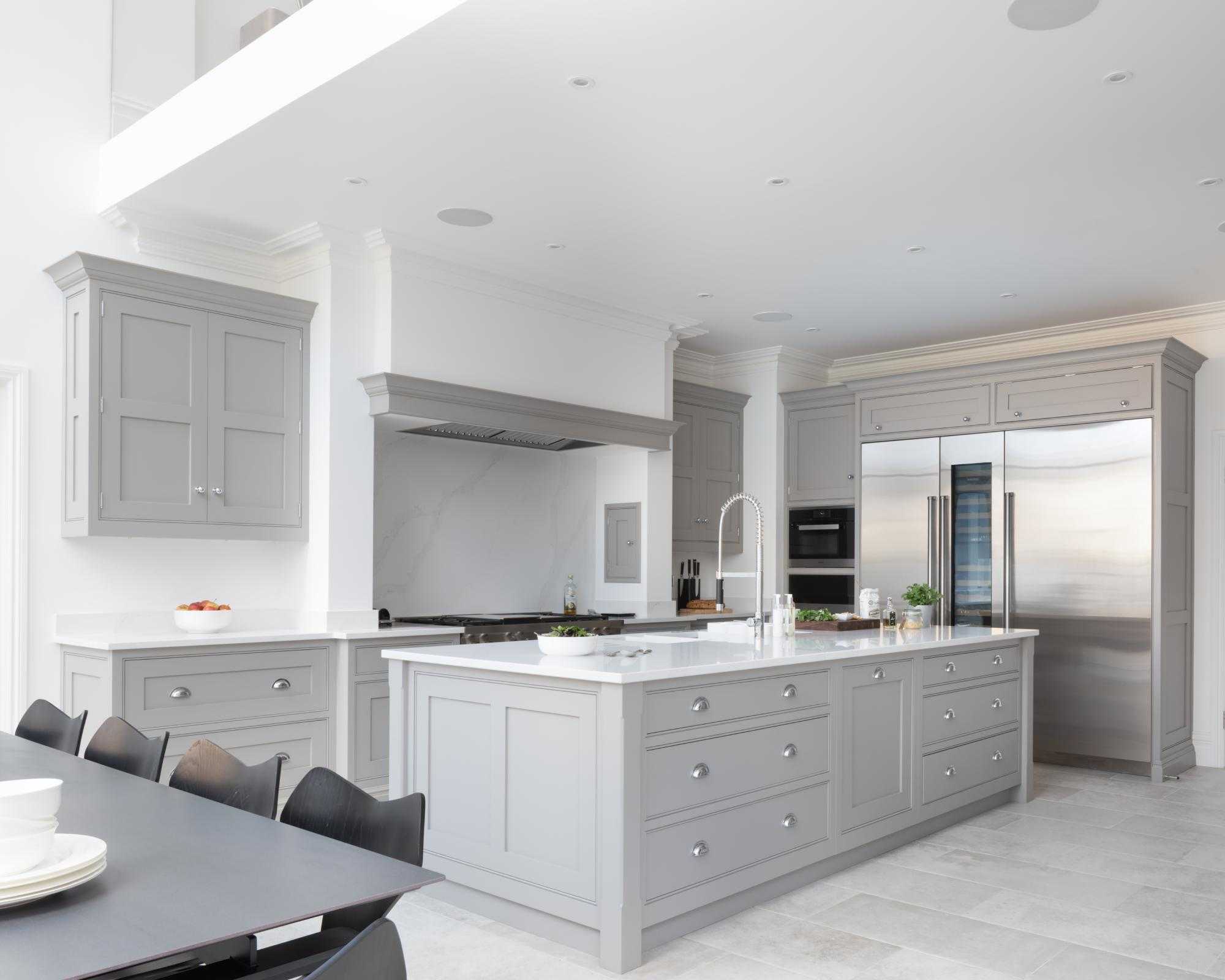 A white and gray open plan kitchen with double height ceiling.