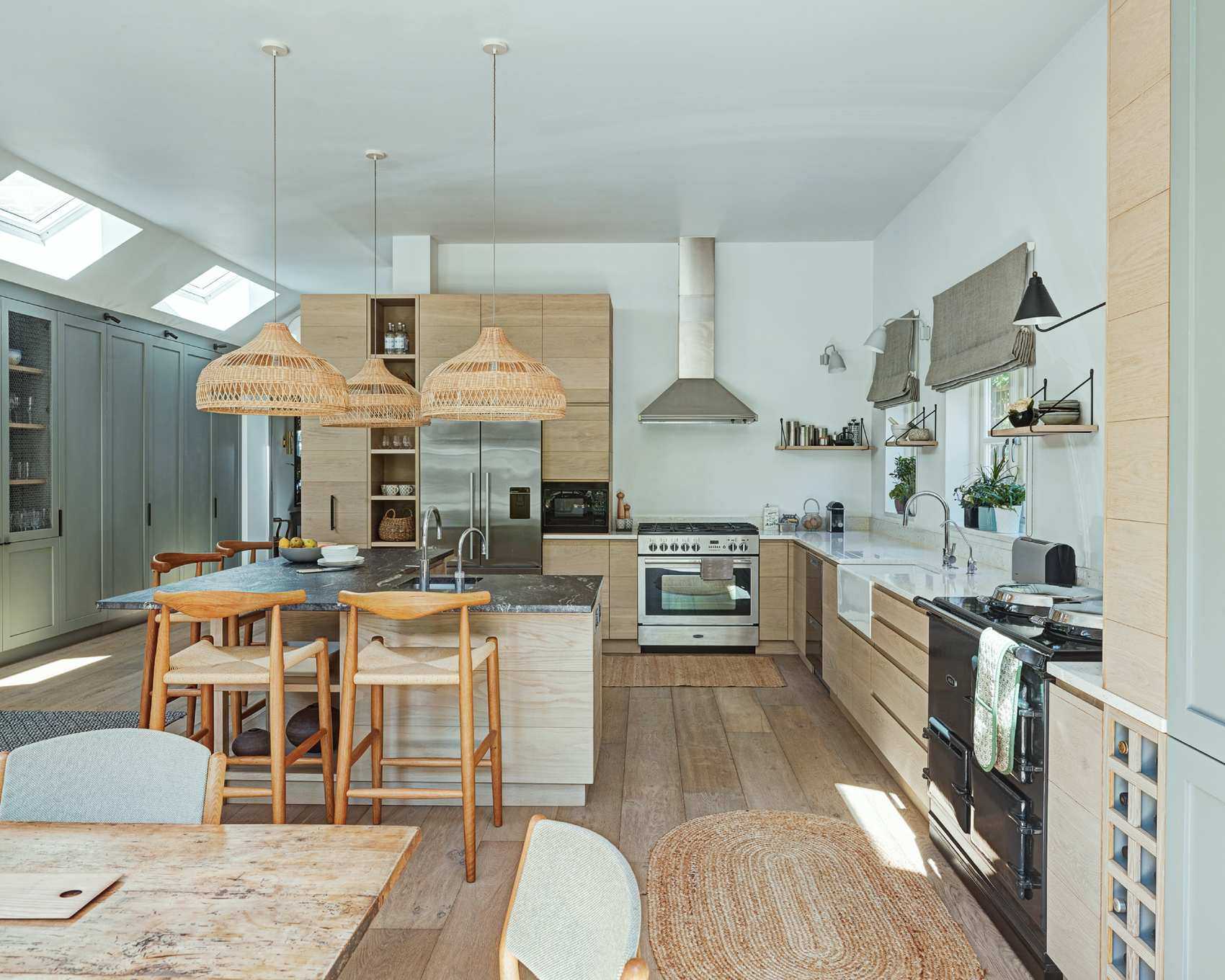An L-shaped breakfast bar in an open plan kitchen with rattan pendant lighting and rugs.