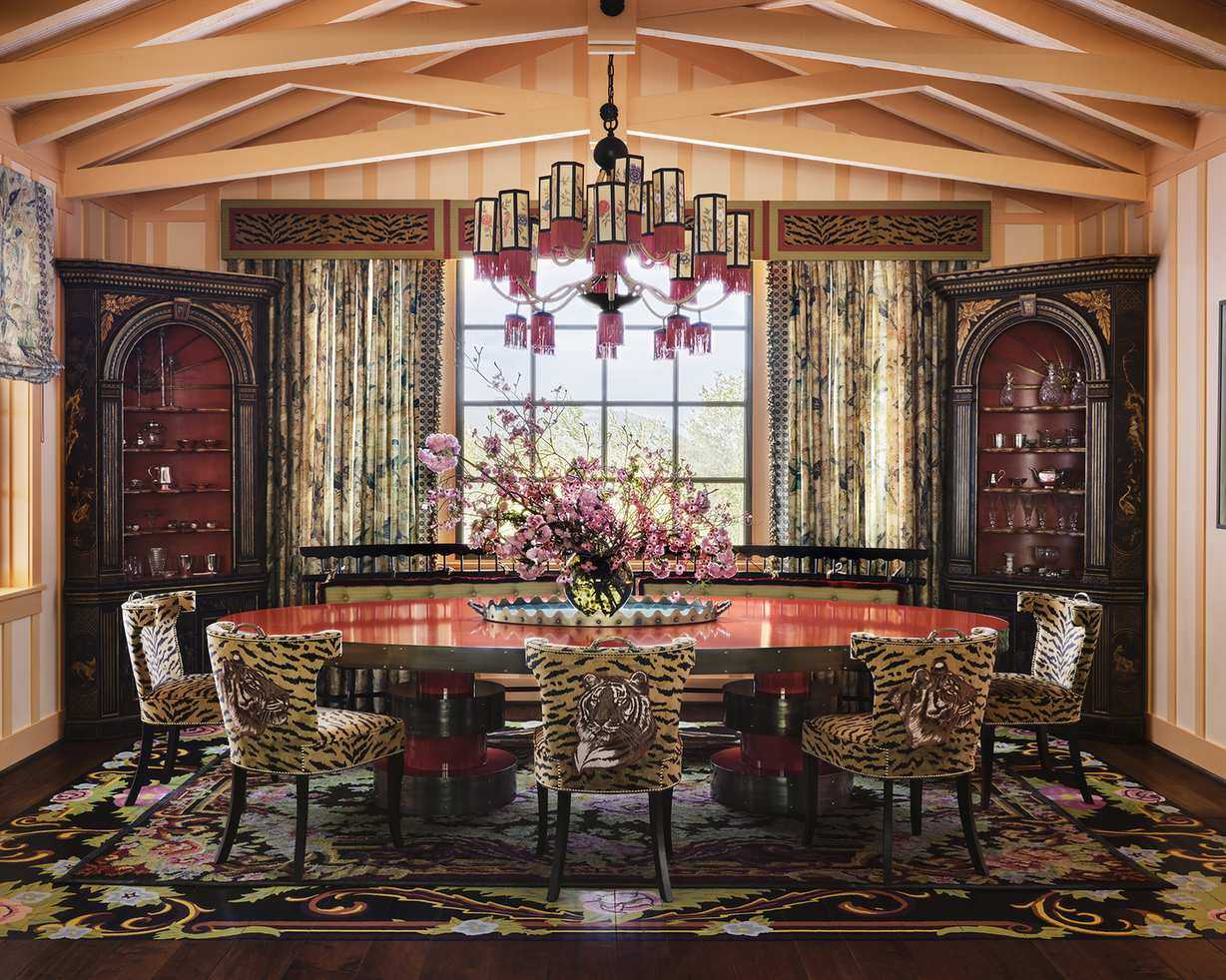 large dining room with leopard print dining chairs and pink chandelier over the table