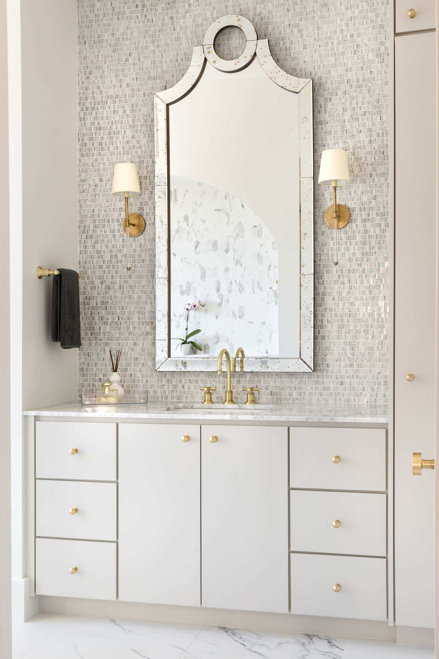A large mirror and glittery mosaic tiles over a cream and gold vanity