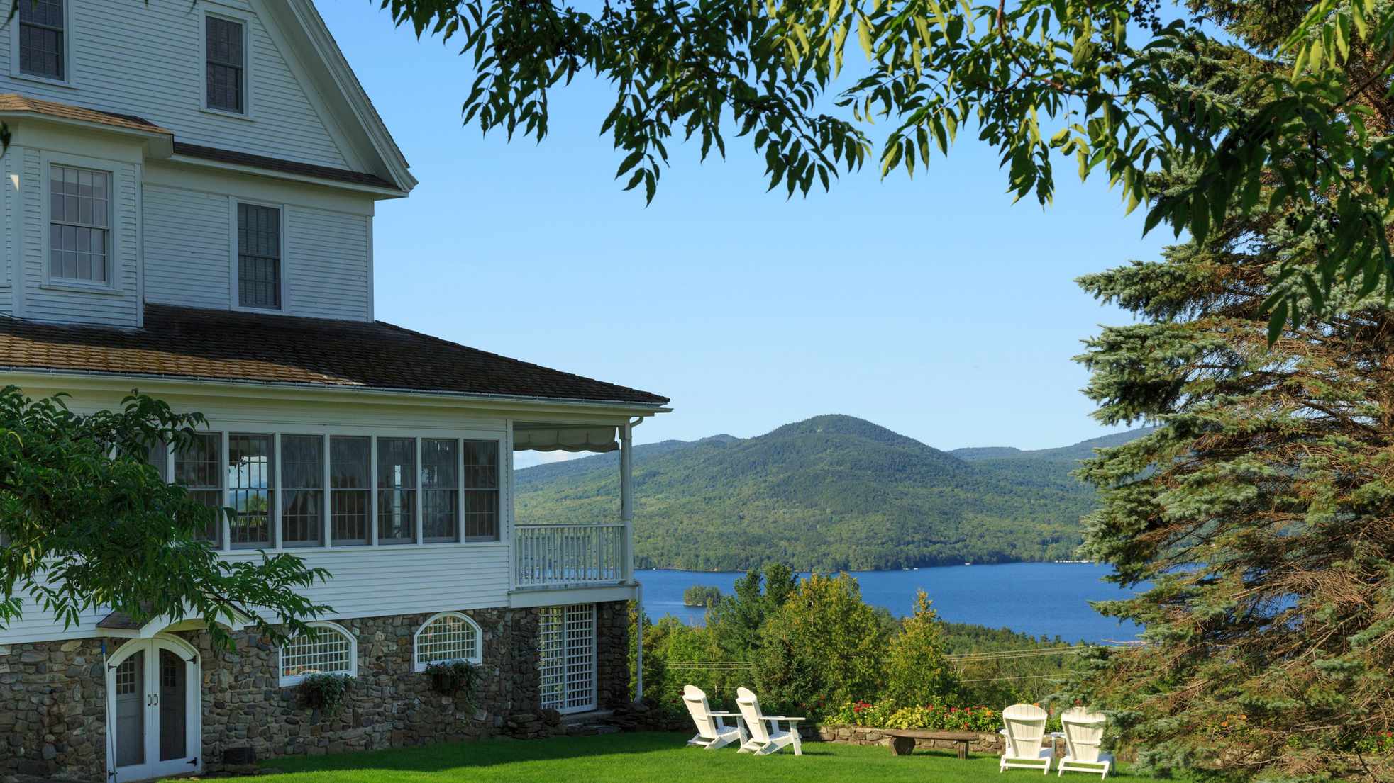 Cape cod home overlooking lake with Adirondack chairs in backyard