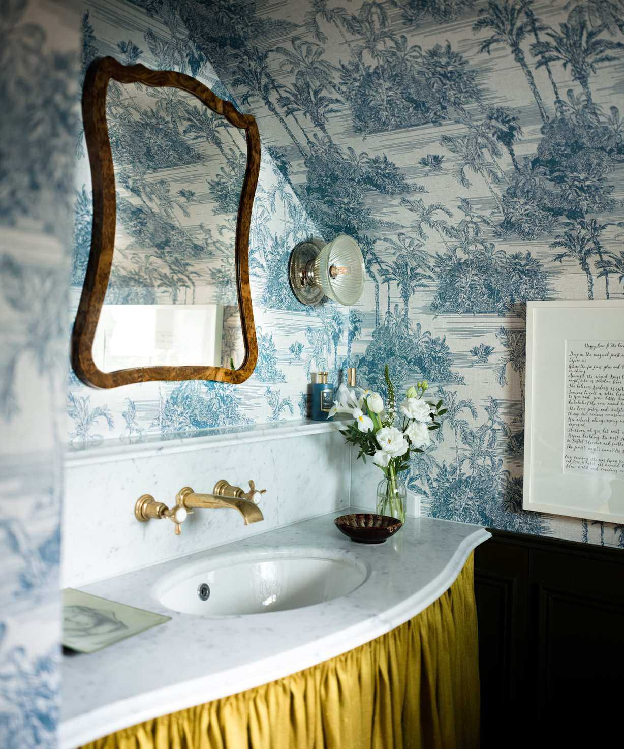 small powder room bathroom with blue and white toile wallpaper, a marble vanity sink with a yellow sink skirt