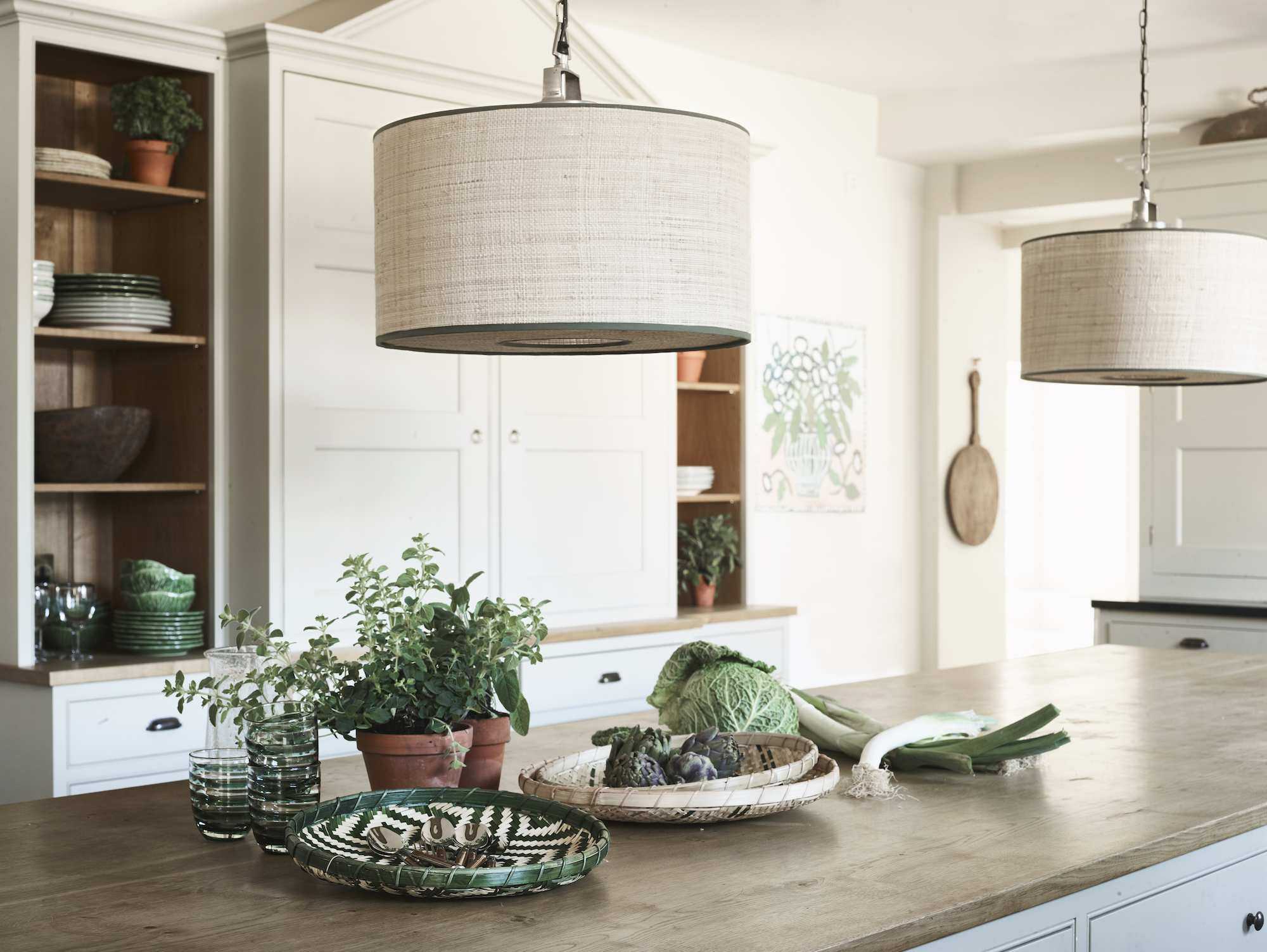 raffia drum pendant shade above kitchen island with wooden countertop, decorated with food and plates