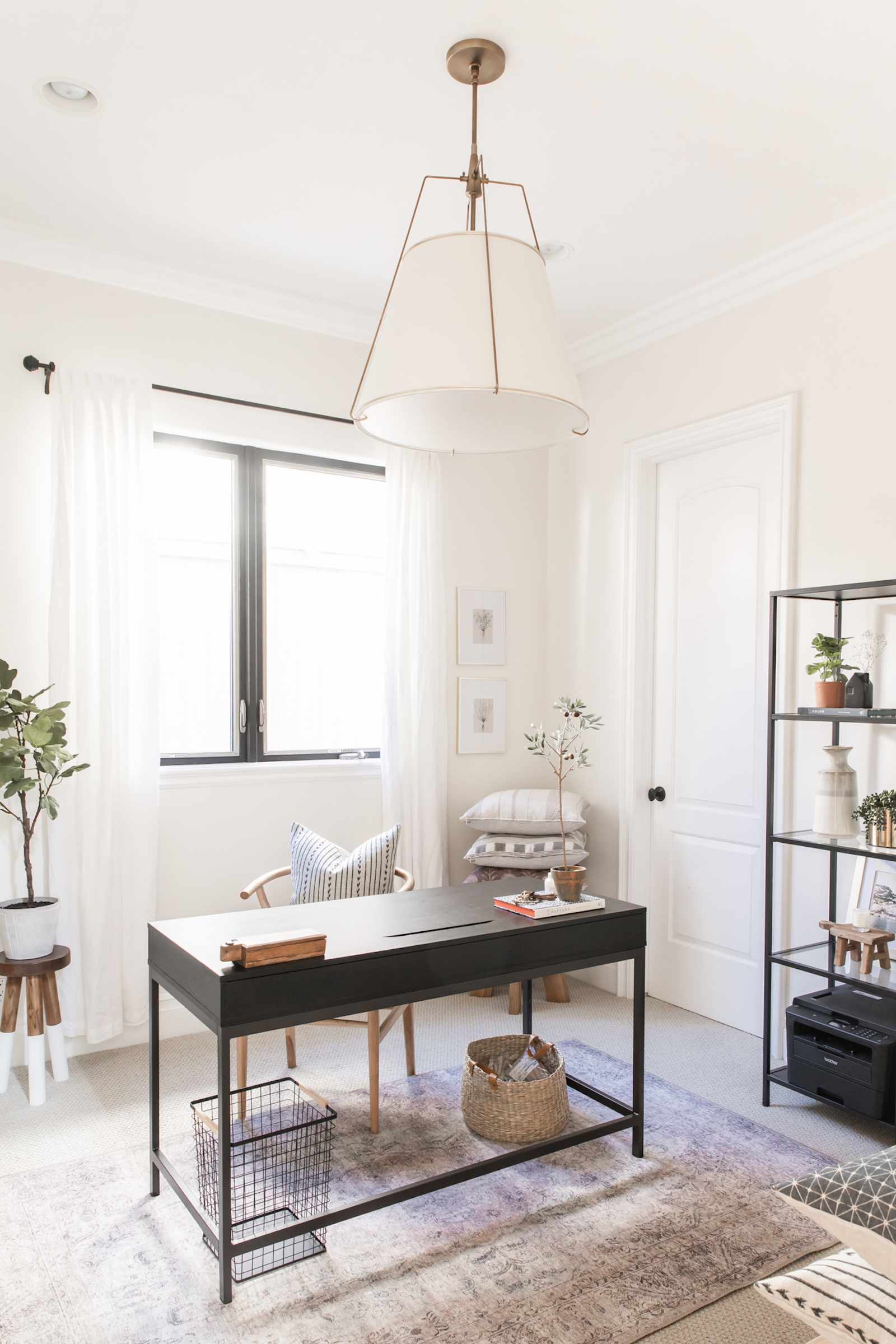 farmhouse home office with large pendant light, black metal desk, rug on cream carpet
