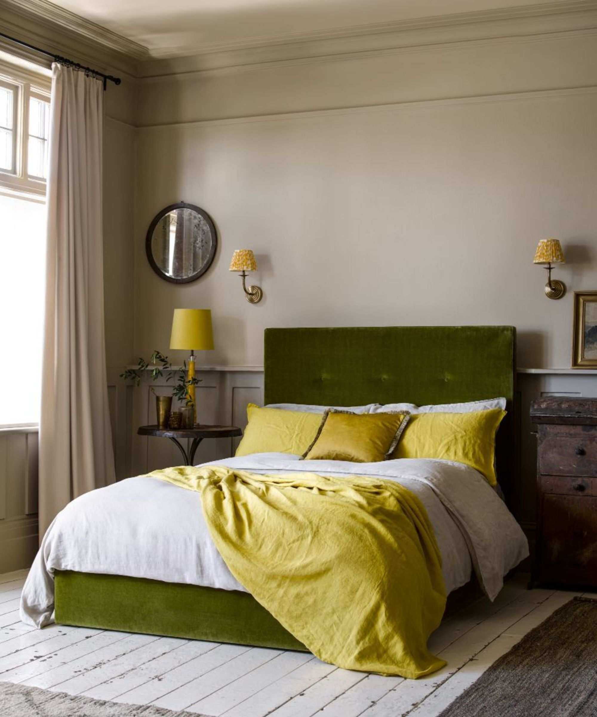Magnolia painted bedroom with green velvet bed and yellow bedding, yellow sconces and yellow bedside lamp