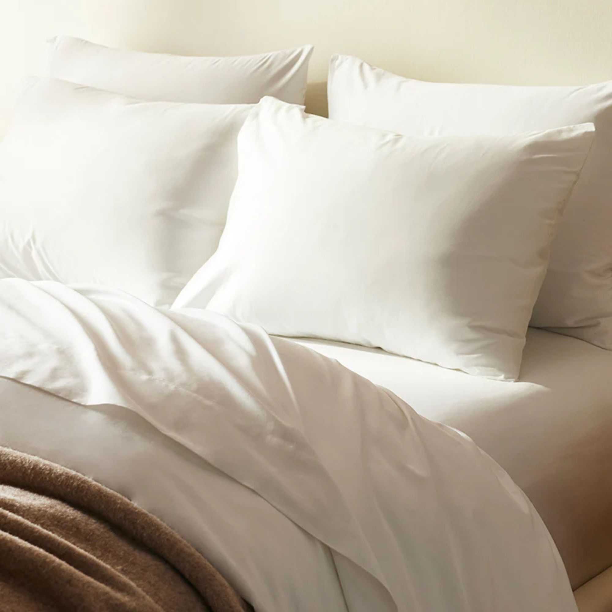 Brooklinen Luxe Core Sheet Set on a bed against a white wall.