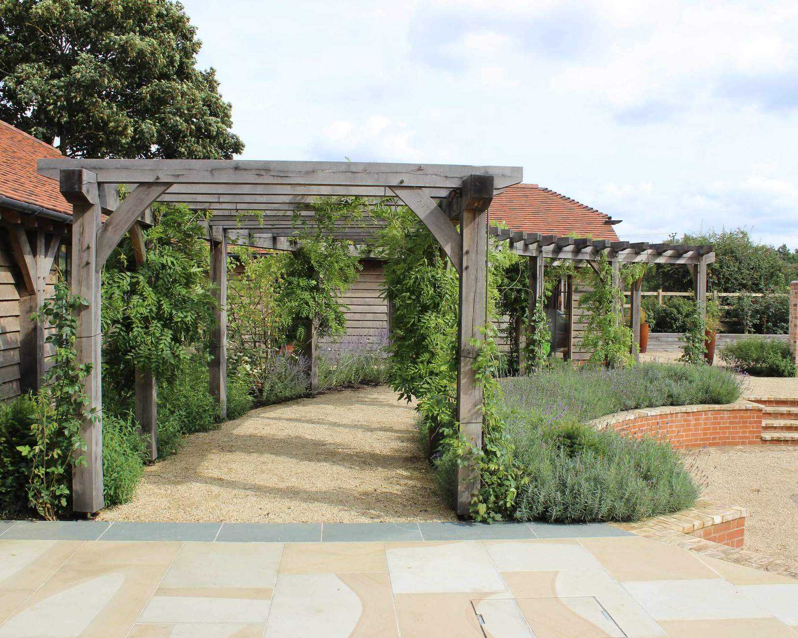 pergola in a country garden along edge of circular patio space designed by Bowles &amp; Wyer
