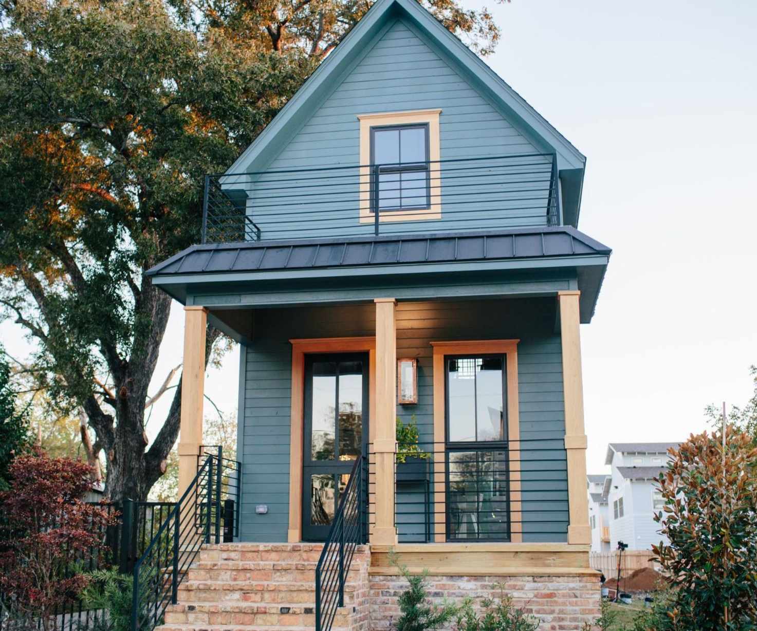 Shotgun house exterior with blue and wood facade and brick steps