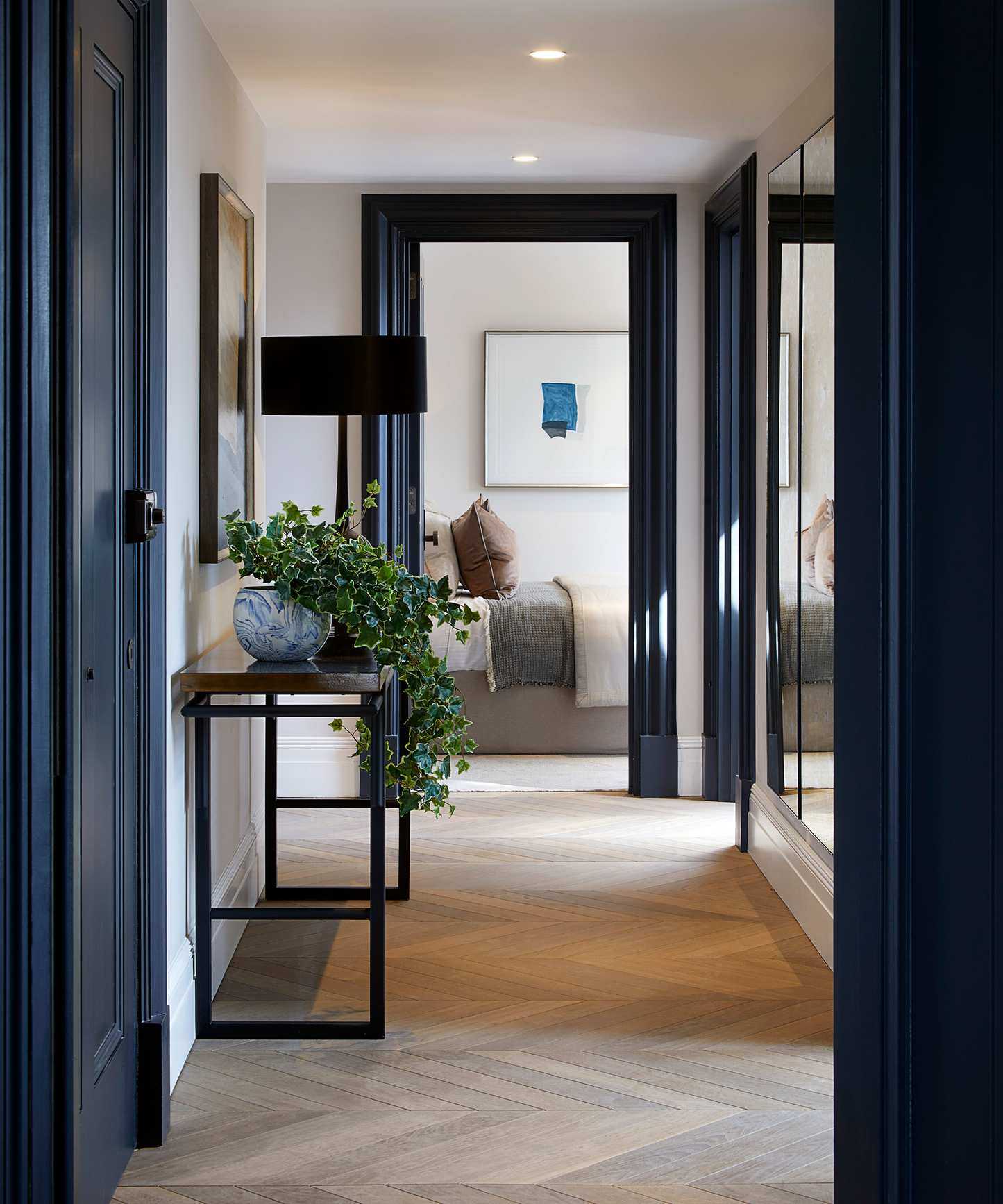 Dark blue paintwork in a small hallway with console table and herringbone flooring.