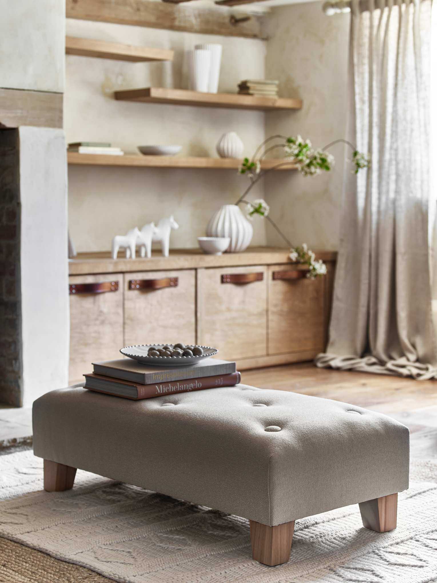farmhouse living room with ottoman, wooden shelving, cream carpet