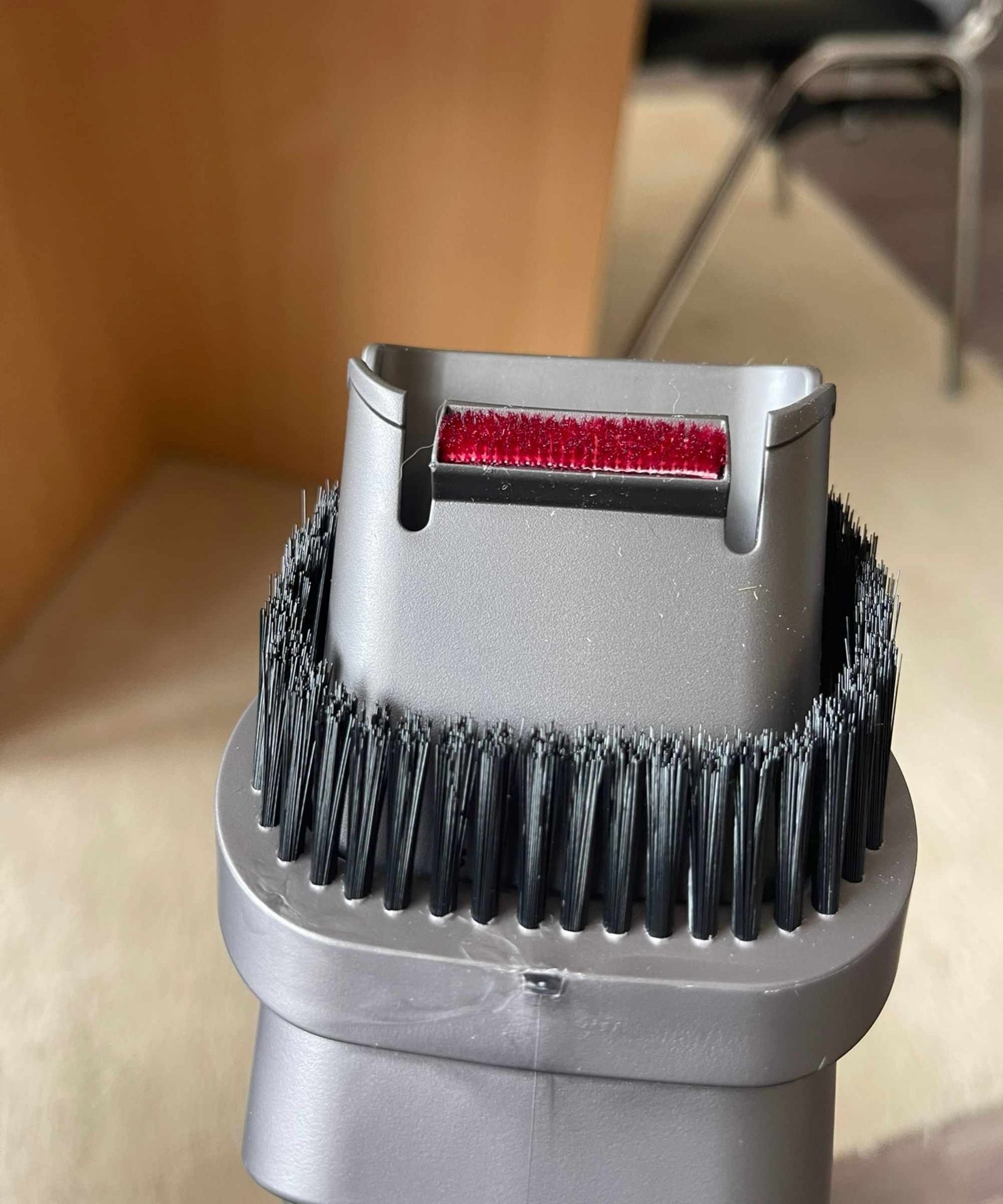 Closeup of the Dyson V11's combination tool vacuum attachment in Bristol ARC, pictured in front of cream rug and wooden table legs.
