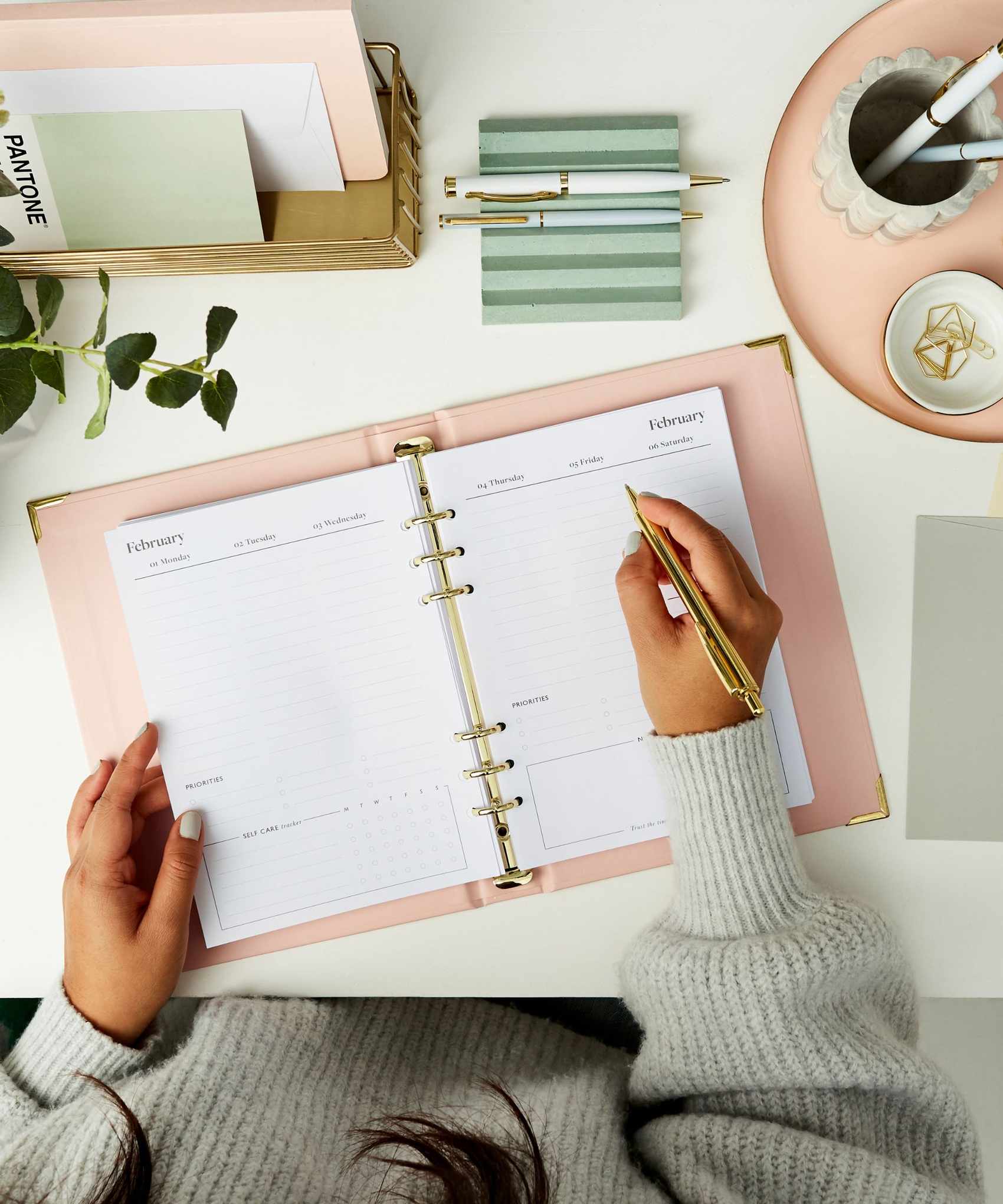 Someone writing in a Personalised Dream Plan Do Life Planner on a white desk surrounded by matching stationary