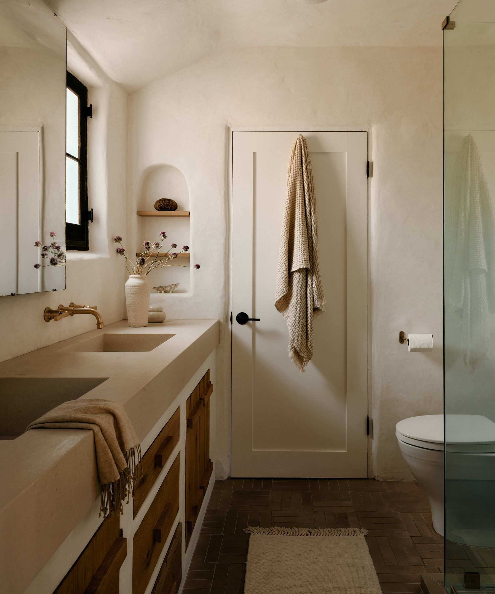 A modern organic bathroom in an Adobe home with plastered walls and a plaster and reclaimed wood vanity