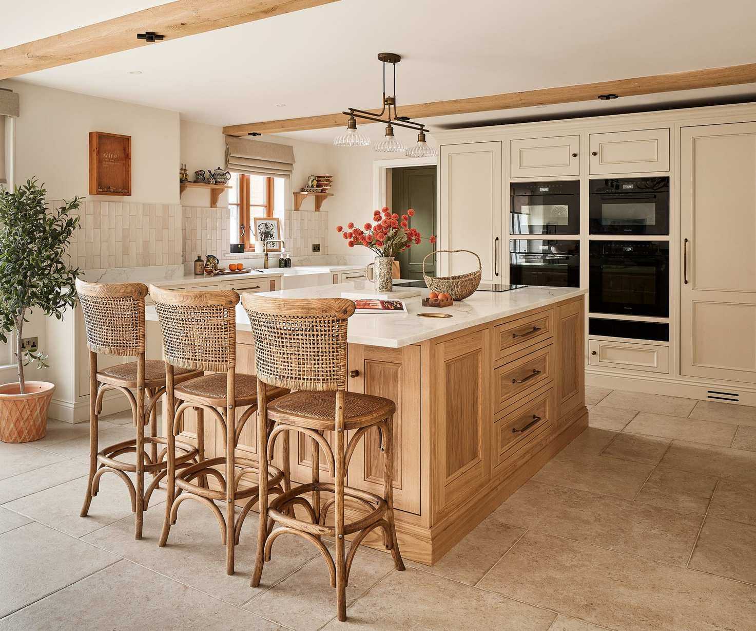 A sociable kitchen with cream cabinets, a wooden island, and tarnishes brass hardware throughout