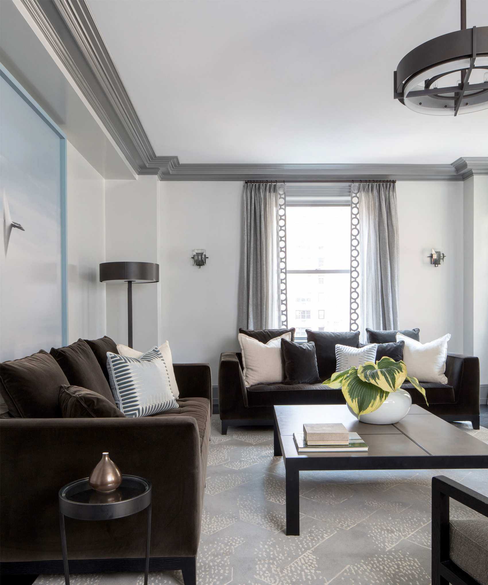 Contemporary living room with white painted walls, gray painted ceiling trim, two black sofas, black square coffee table, blue patterned rug