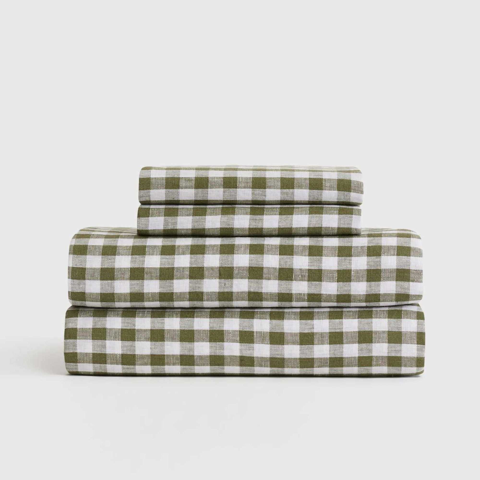 A folded stack of Quince European linen olive gingham sheets