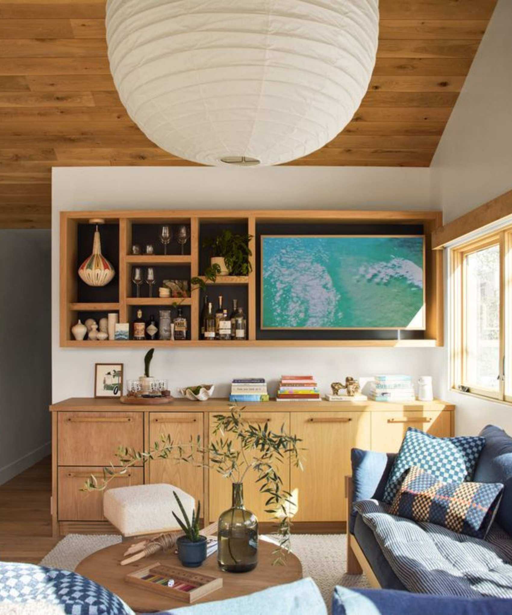 White living room with wooden paneled ceiling, wooden wall shelving and console and blue couch