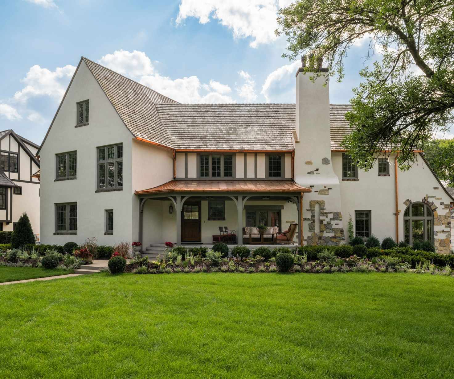 Tudor revival home with porch and lawn