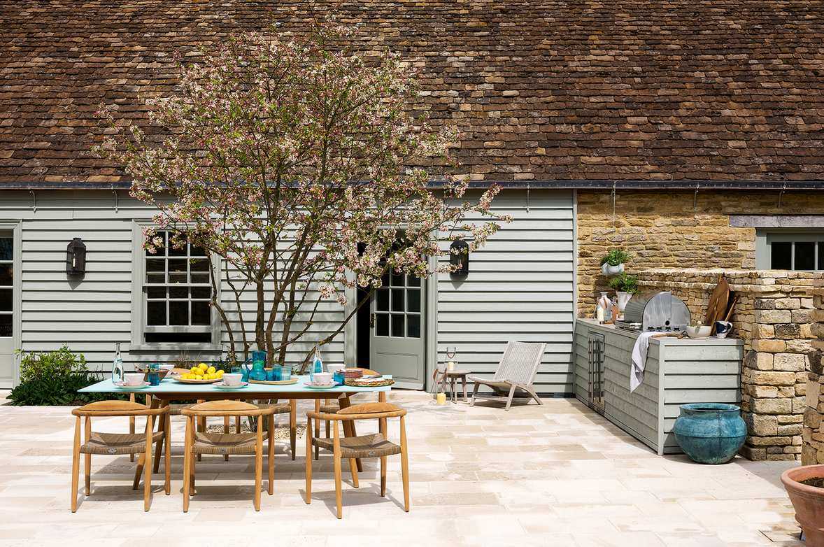 Outdoor kitchen area with countertop grill, dining table and chairs
