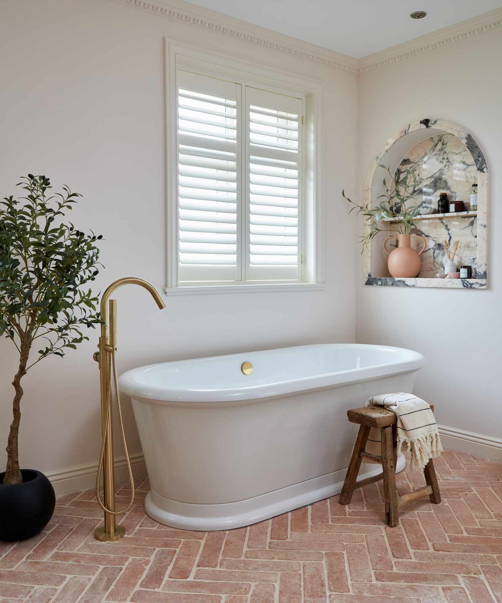 terracotta floor bathroom with marble niche and freestanding bathtub