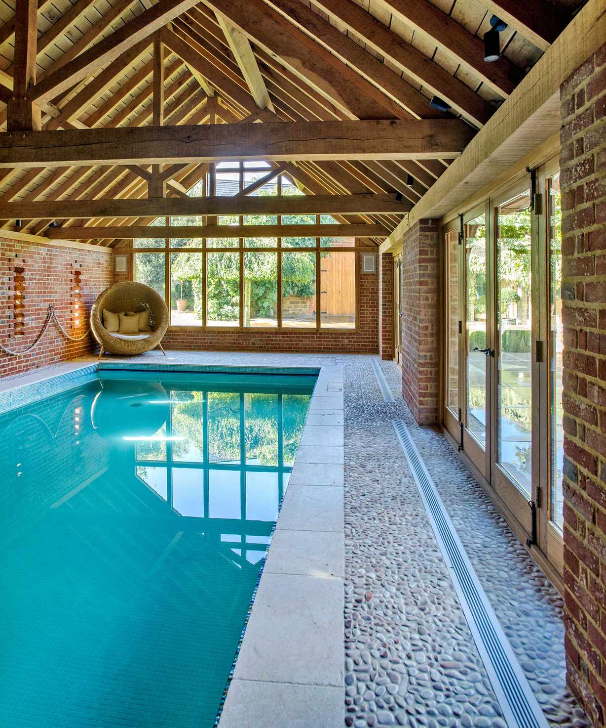 An example of pool landscaping ideas showing an indoor pool with wooden beams and a non-slip floor