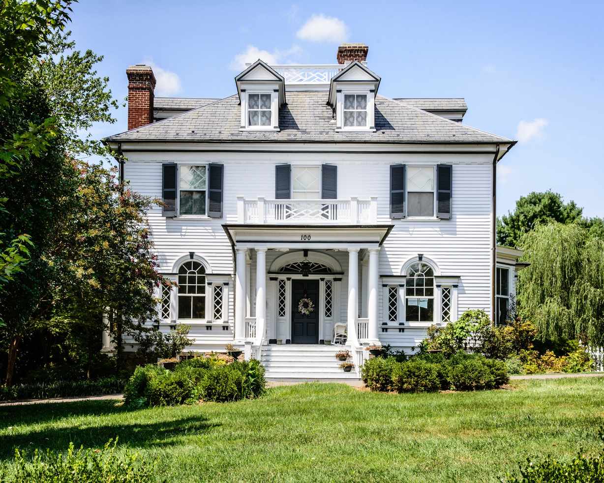 white wooden house with porch with columns, balcony and dormer windows
